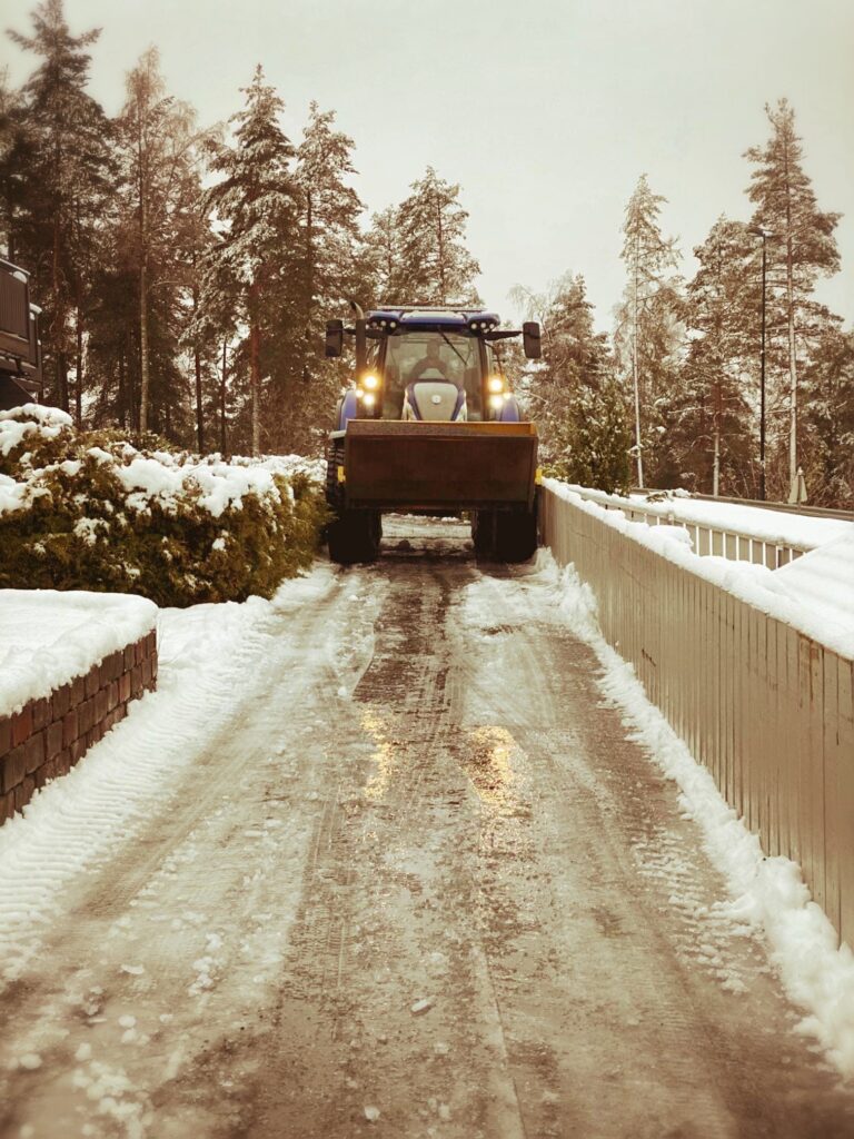 Traktor med brøyteskjær rydder snø på vei en vinterdag