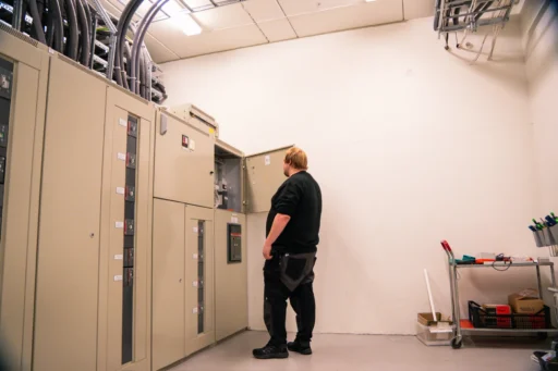 Vaktmester fra Bryn Bydrift sjekker tekniske skap i et lyst teknisk rom
